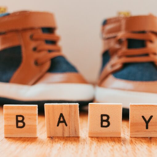 Letters That Say Baby With Little Boy Shoes In Background Illuminated By A Golden Hue