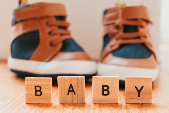 Letters That Say Baby With Little Boy Shoes In Background Illuminated By A Golden Hue