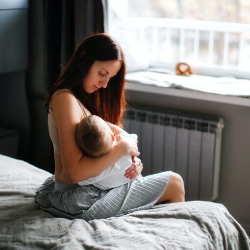 Mother And Baby In The Bedroom On The Bed, Mother Breastfeeds Baby,