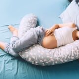 Pregnant Woman Relaxing Or Sleeping With Belly Support Pillow In Bed. Pregnancy Concept.